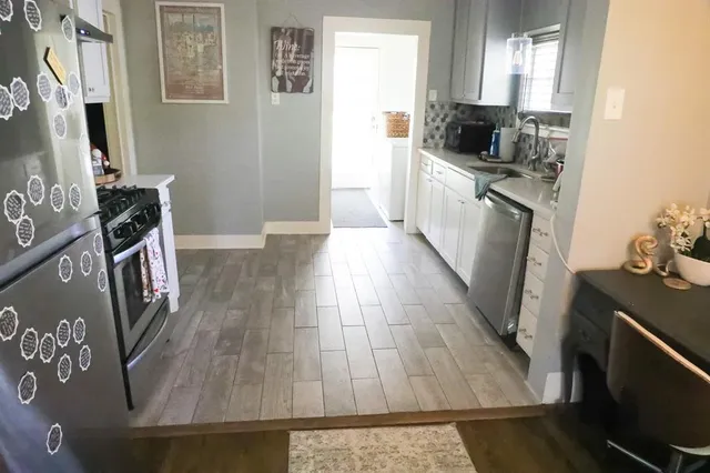 a kitchen with wooden floor and black appliances