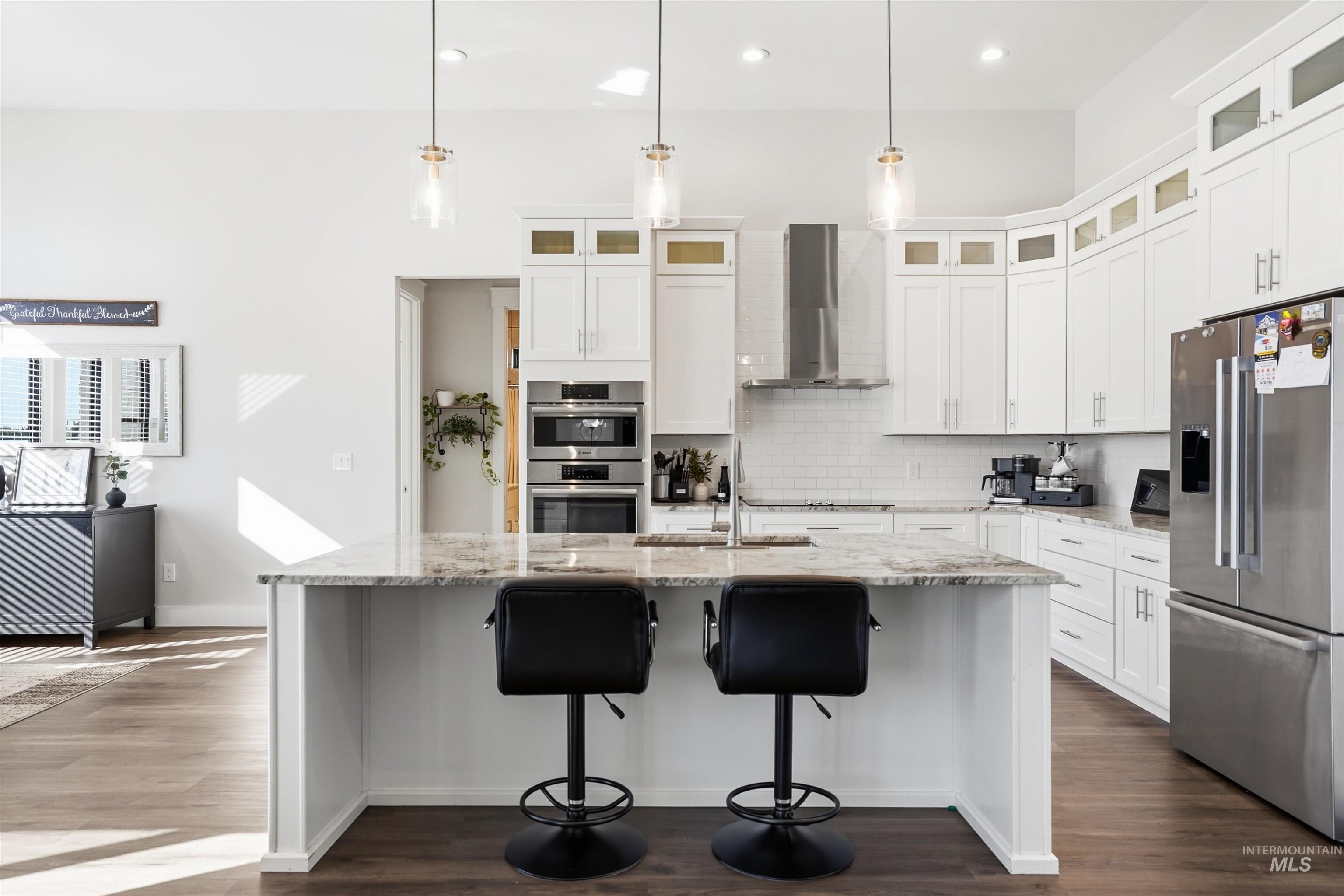 320 West Homedale Road Caldwell, ID 83607 - Photo 11 of 48 Kitchen with stainless steel appliances, light stone counters, a center island with sink, white cabinetry, and dark wood-type flooring