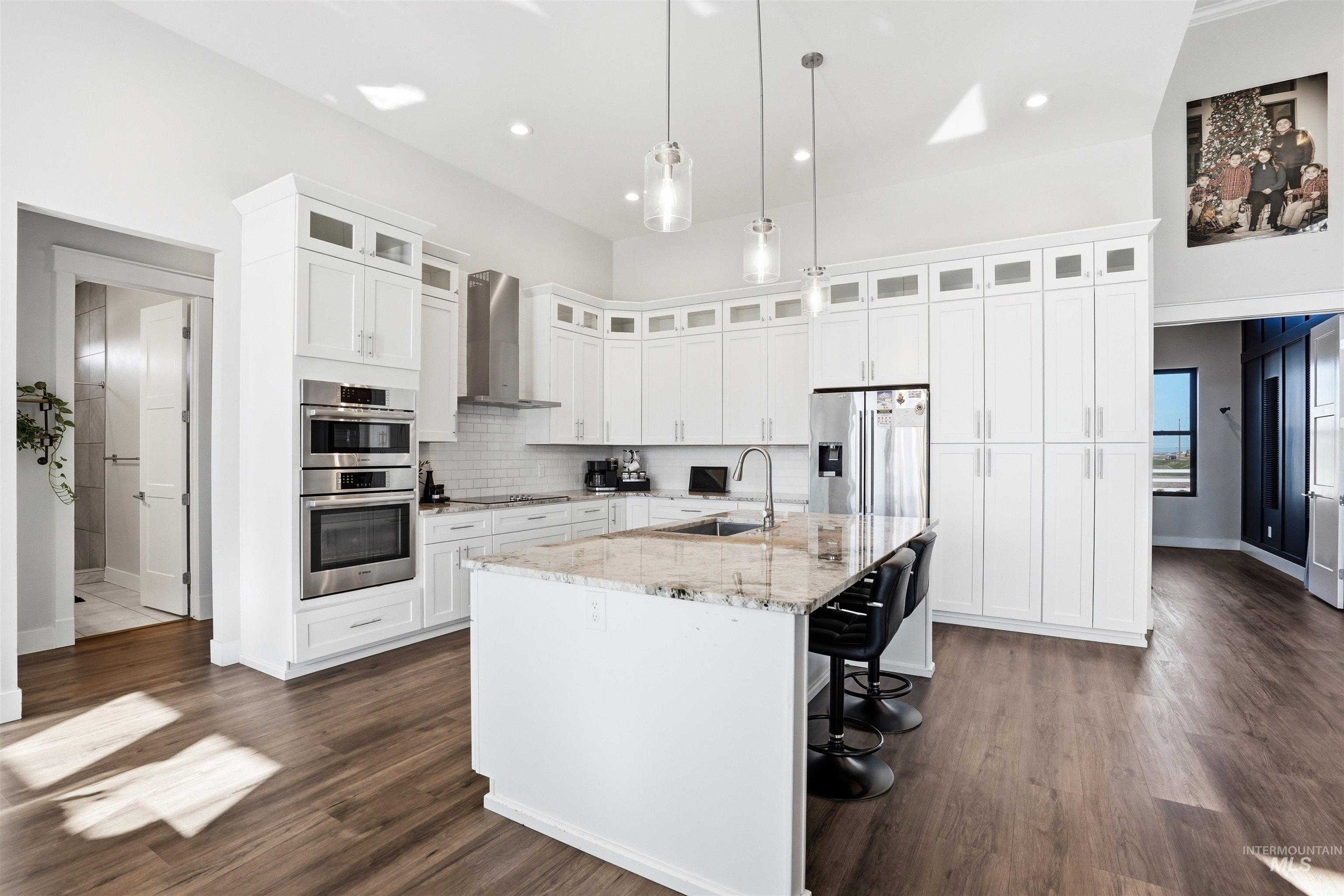 320 West Homedale Road Caldwell, ID 83607 - Photo 13 of 48 Kitchen featuring light stone countertops, stainless steel appliances, a center island with sink, hanging light fixtures, and white cabinetry