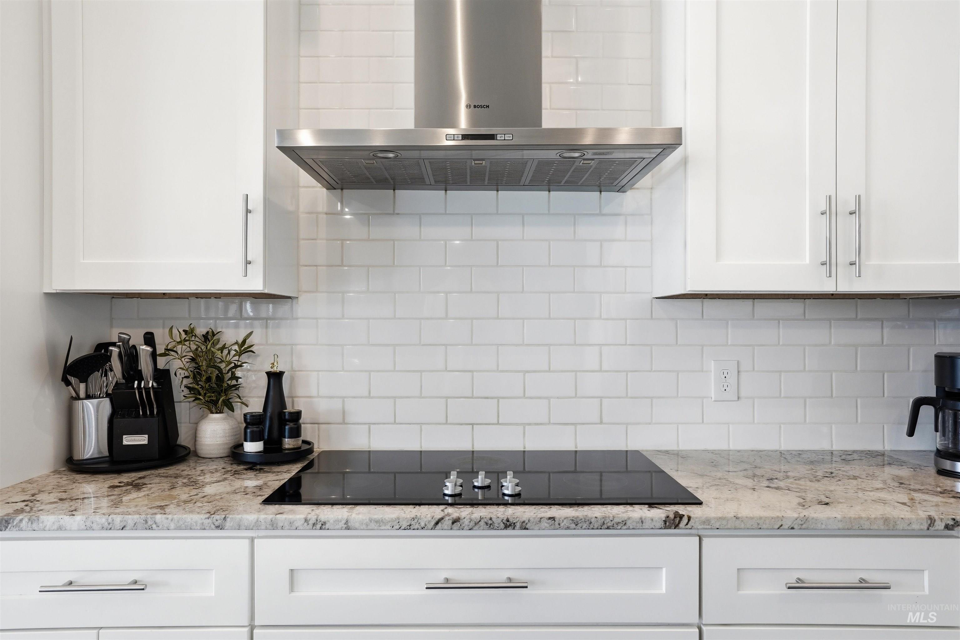 320 West Homedale Road Caldwell, ID 83607 - Photo 14 of 48 Kitchen with light stone countertops, white cabinets, black electric cooktop, and tasteful backsplash