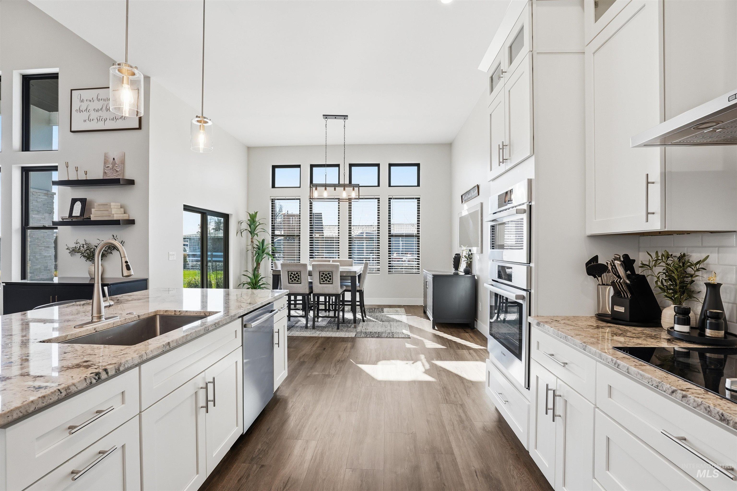 320 West Homedale Road Caldwell, ID 83607 - Photo 15 of 48 Kitchen with white cabinetry, light stone counters, dark wood-style flooring, pendant lighting, and range hood