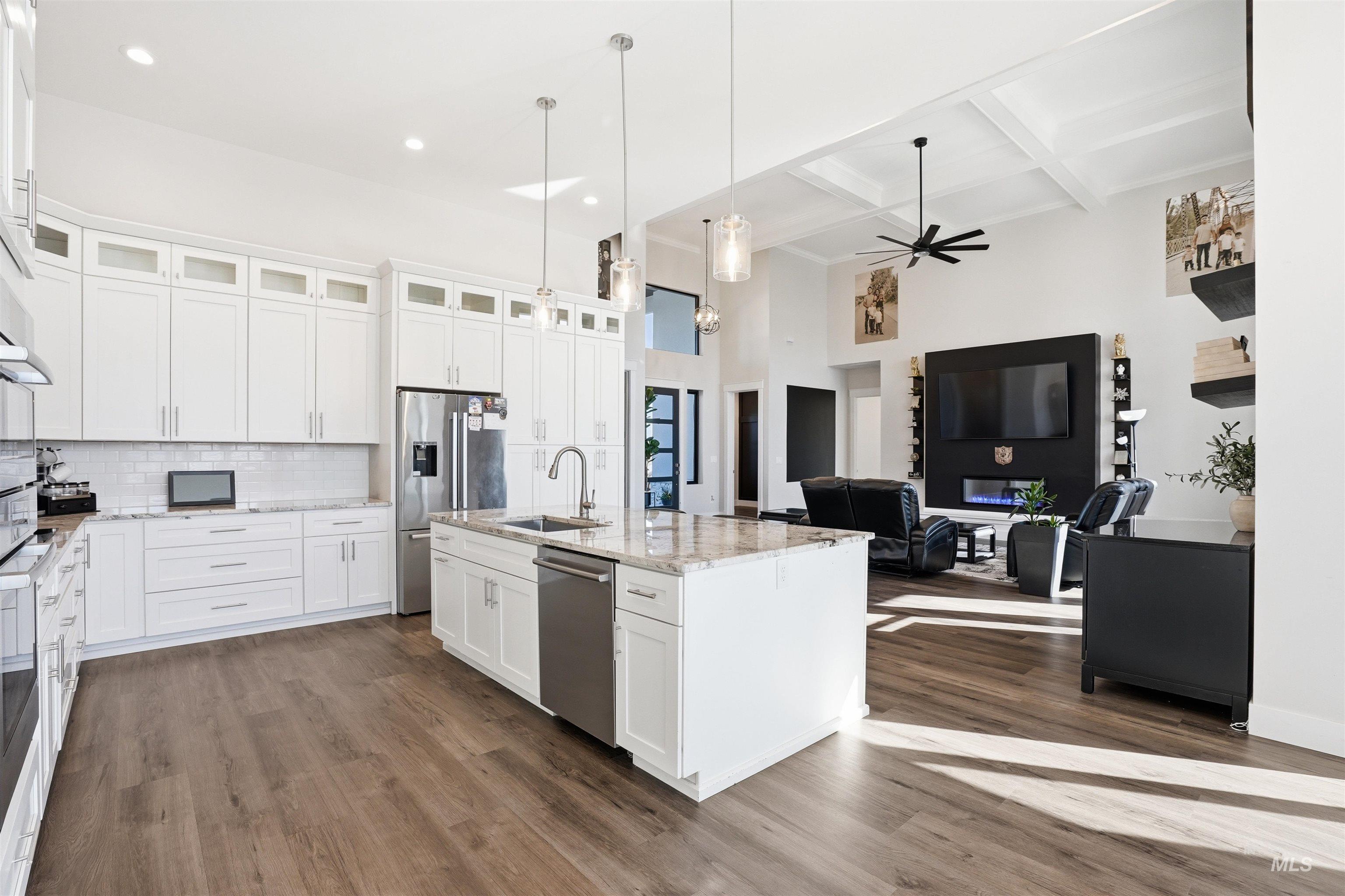 320 West Homedale Road Caldwell, ID 83607 - Photo 48 of 48 Kitchen featuring open floor plan, coffered ceiling, white cabinets, an island with sink, and light stone counters