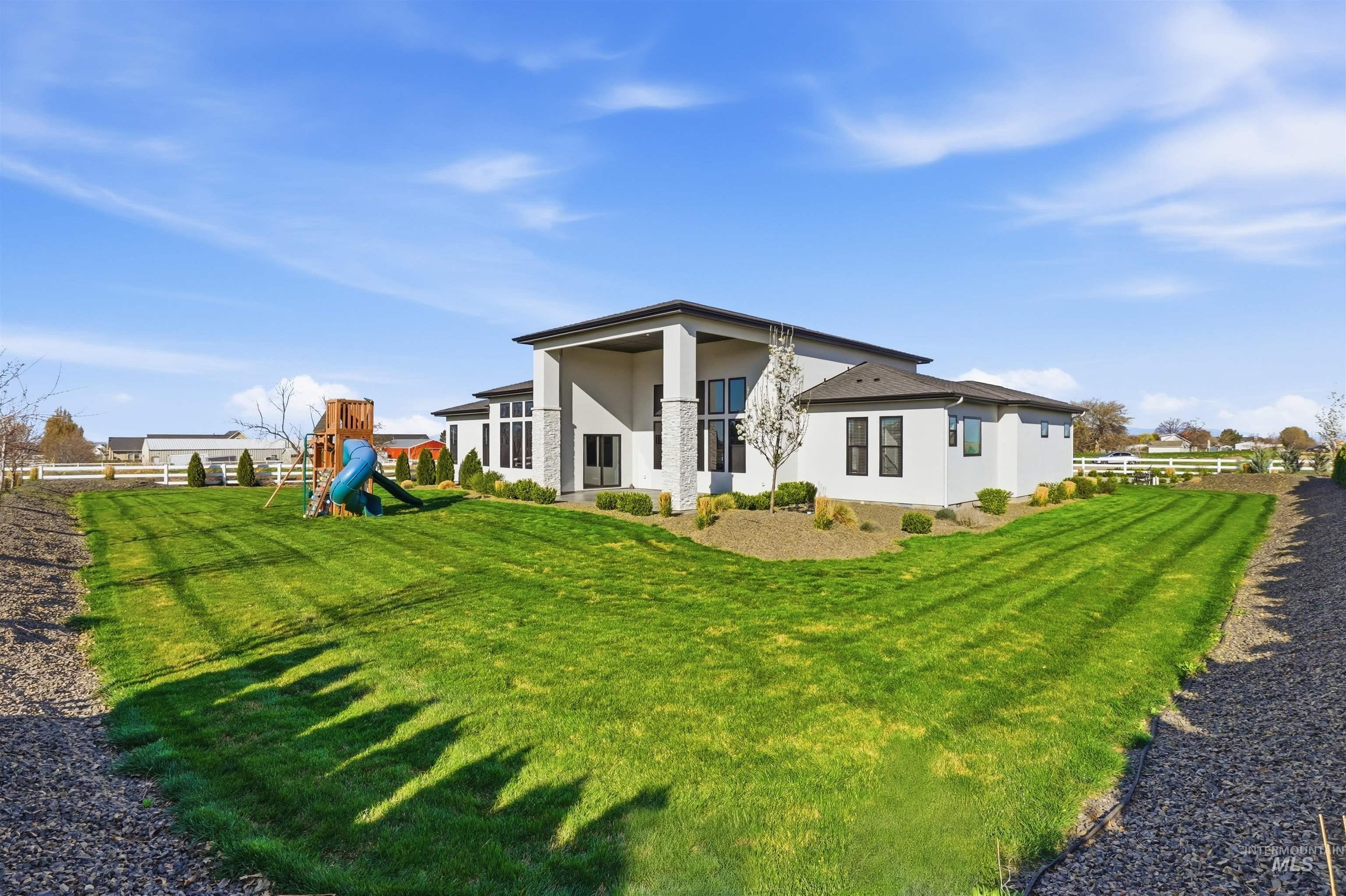 320 West Homedale Road Caldwell, ID 83607 - Photo 38 of 48 Rear view of house featuring a playground, stucco siding, and a lawn