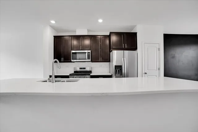 a large white kitchen with a sink and stainless steel appliances