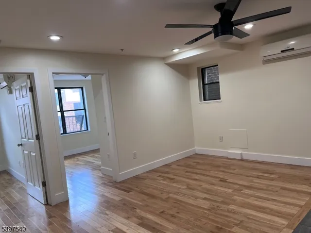 a view of an empty room with wooden floor and a window