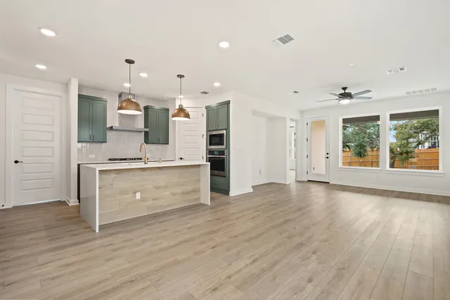 a large kitchen with granite countertop a stove a sink refrigerator and a wooden floor