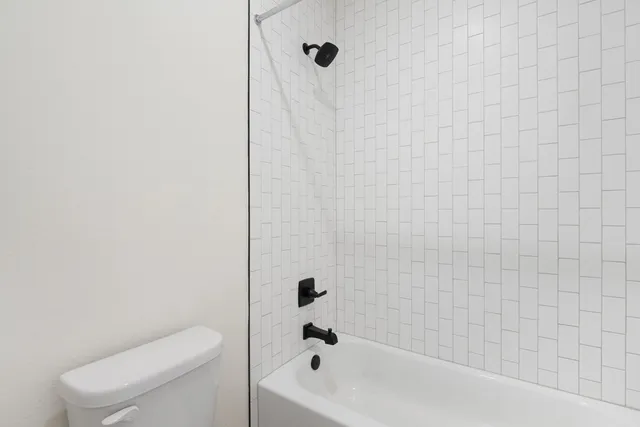 a bathroom with a granite countertop sink a toilet and shower