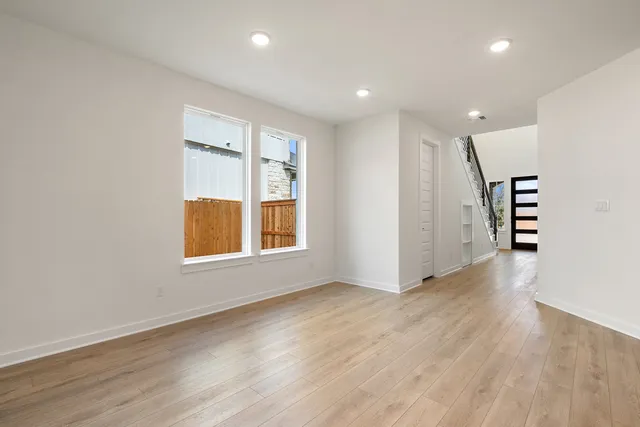 a view of an empty room with wooden floor and a ceiling fan