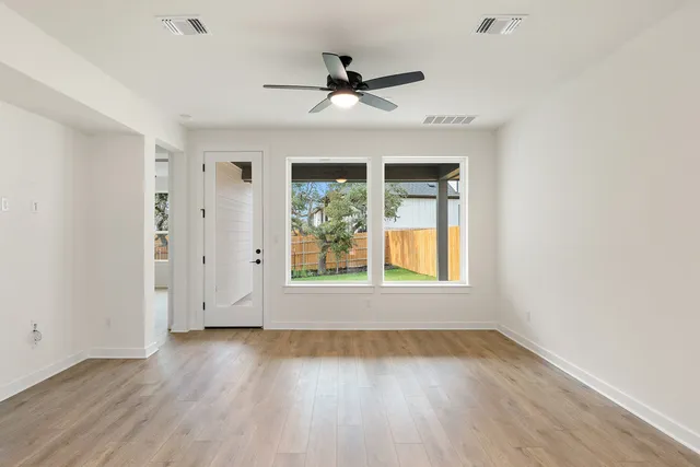 a view of an empty room with wooden floor and a window