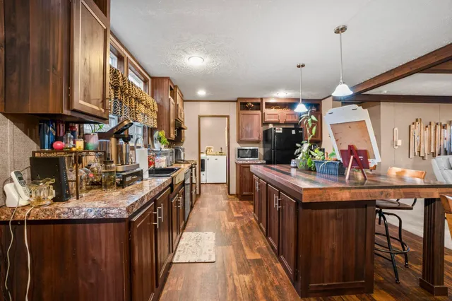 a kitchen with stainless steel appliances granite countertop a kitchen island a stove a sink dishwasher and cabinets with wooden floor