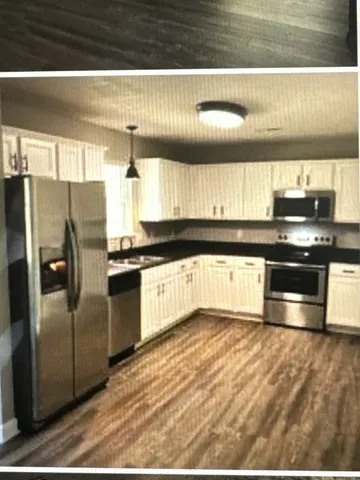 a kitchen with granite countertop a refrigerator and wooden cabinets