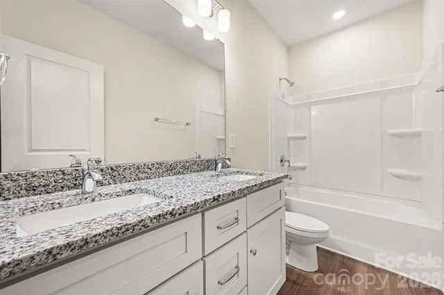 a bathroom with a granite countertop sink mirror vanity and toilet