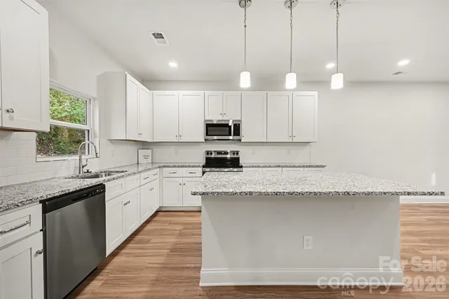 a large kitchen with granite countertop a sink a counter top space appliances and cabinets