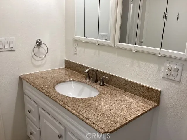 a bathroom with a granite countertop sink and a mirror