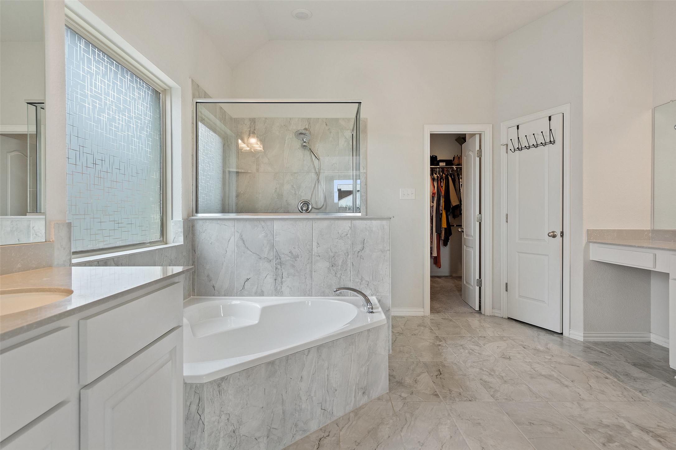 4101 Gildas Path Pflugerville, TX 78660 - Photo 10 of 16 Bathroom with vanity, a marble finish shower, a bath, a walk in closet, and light marble finish flooring leading to a large walk-in closet