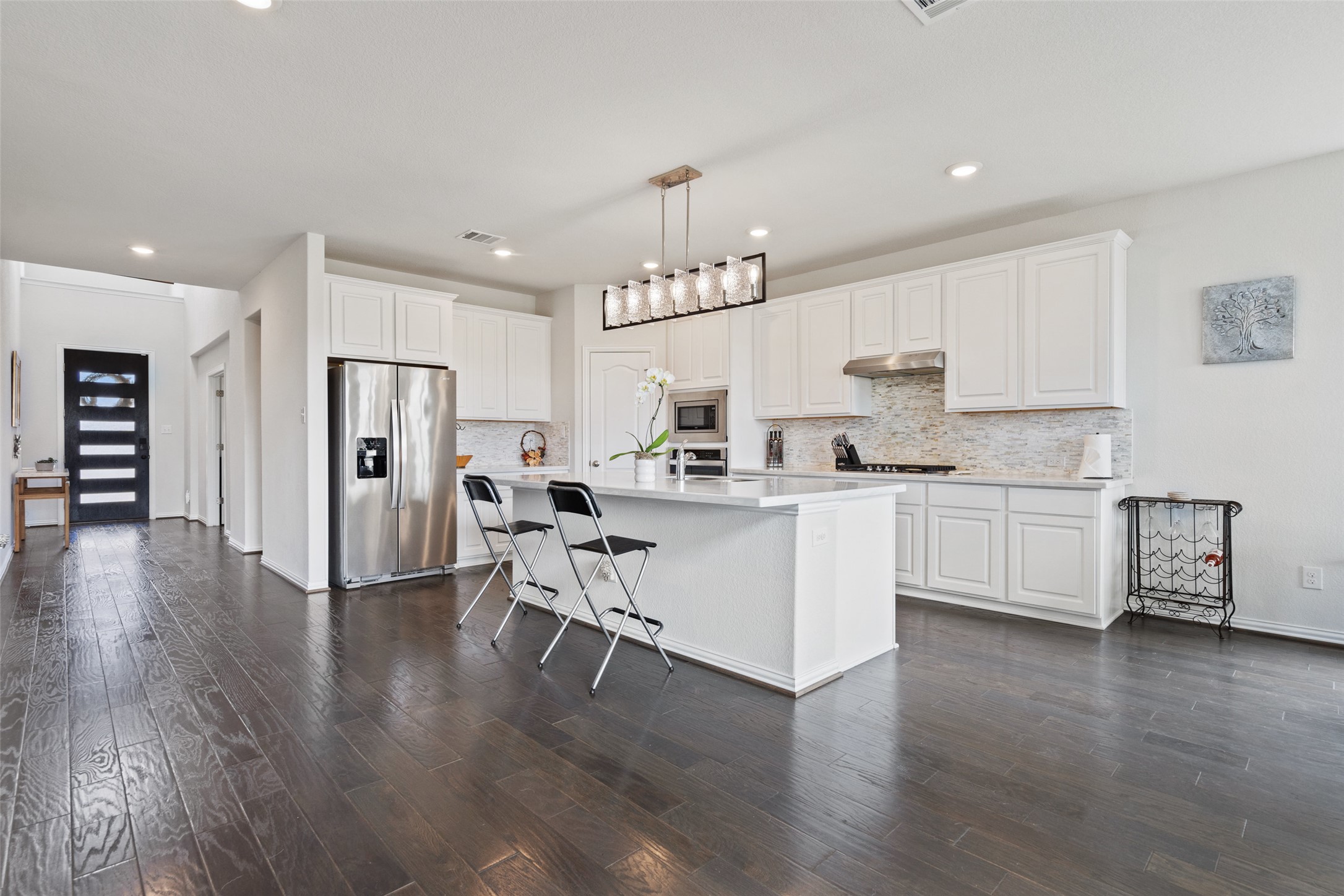 4101 Gildas Path Pflugerville, TX 78660 - Photo 4 of 16 Kitchen featuring stainless steel appliances, white cabinets, a kitchen bar, a kitchen island with sink, and hanging light fixtures