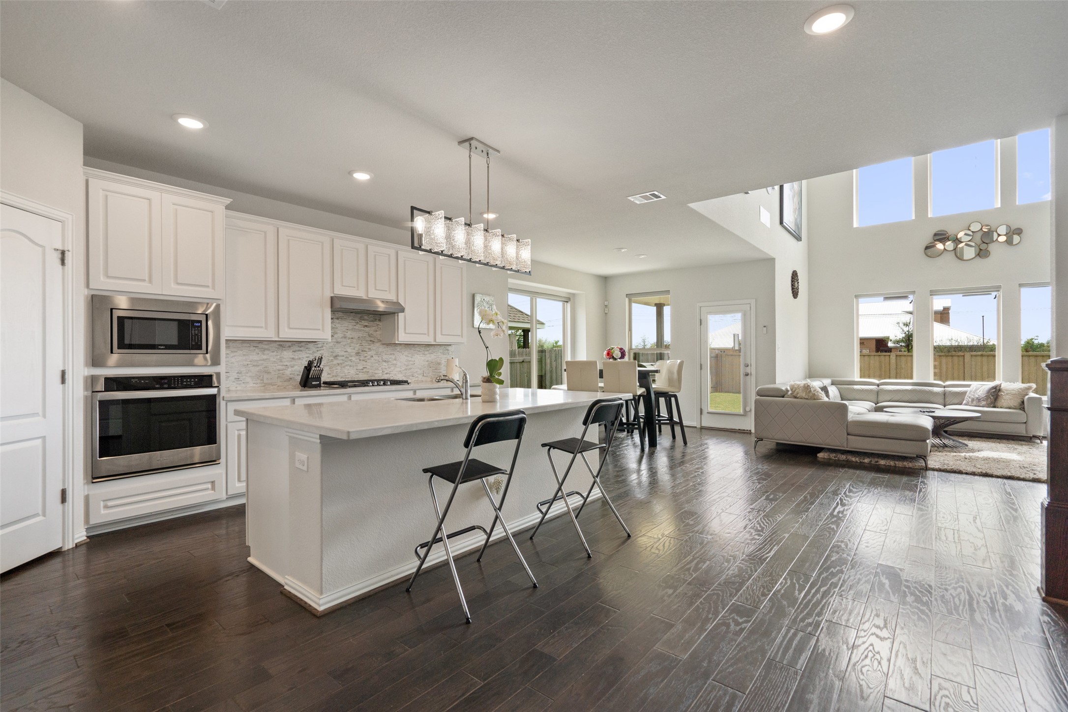 4101 Gildas Path Pflugerville, TX 78660 - Photo 16 of 16 Kitchen featuring stainless steel appliances, open floor plan, white cabinets, a breakfast bar area, and backsplash