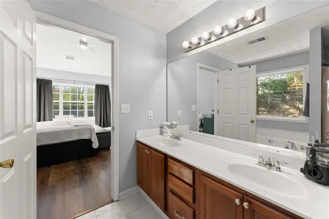 a en suite bathroom with a double vanity sink large mirror and a bathtub