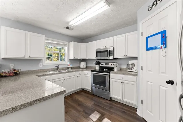 a kitchen with granite countertop white cabinets and white appliances