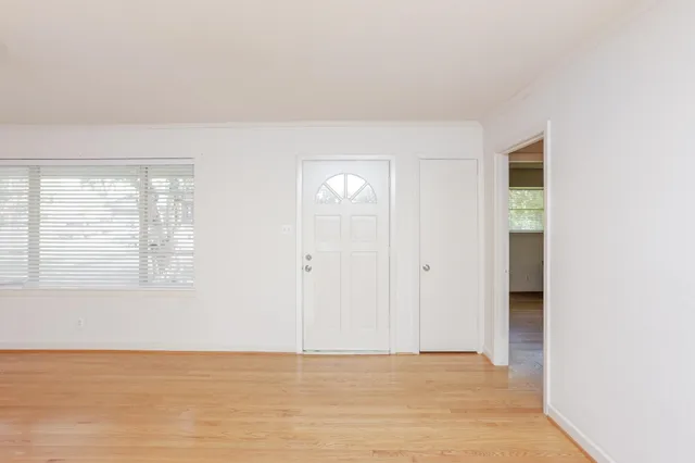 a view of an empty room with window and wooden floor