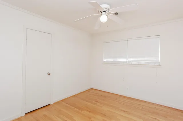 an empty room with wooden floor fan and windows