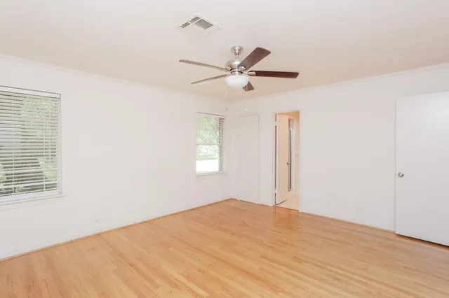 a view of empty room with wooden floor and ceiling fan