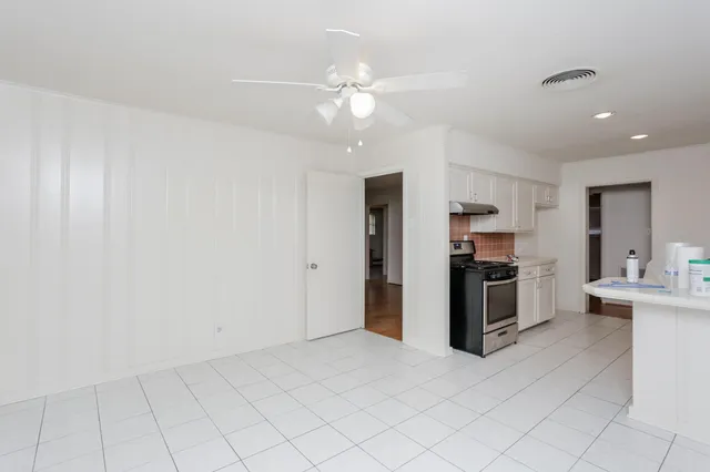a view of kitchen with refrigerator cabinets and stove top oven