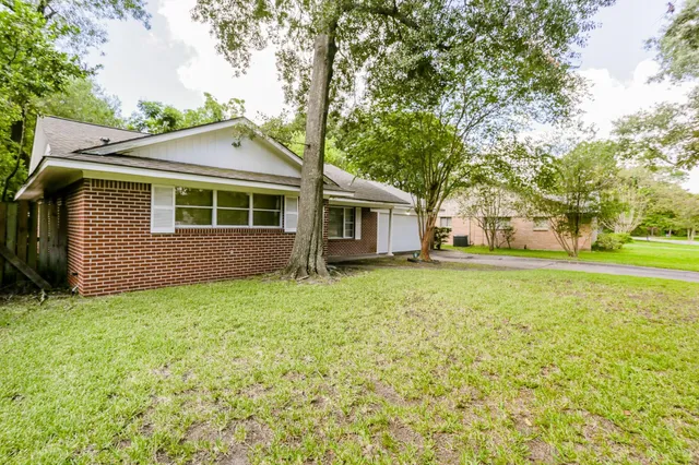 a view of a house with backyard and trees