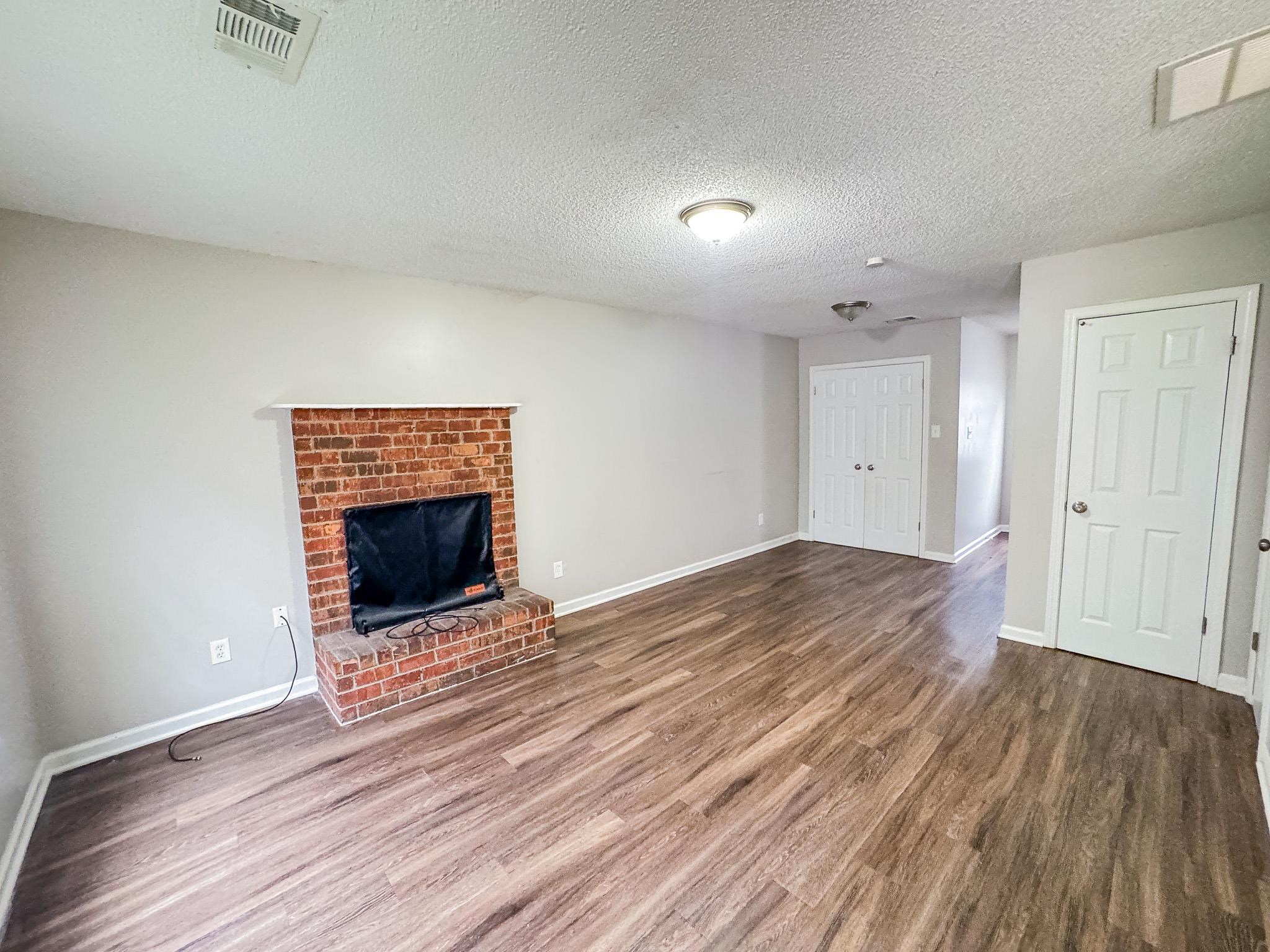3592 Christine Road Memphis, TN 38118 - Photo 2 of 13 Living area featuring a brick fireplace with a white mantel, wood-finish flooring, and light gray wall paint