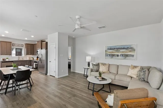 a living room with furniture and a dining table with wooden floor