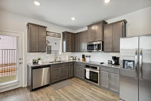 a kitchen with stainless steel appliances a sink a stove a refrigerator cabinets and a window