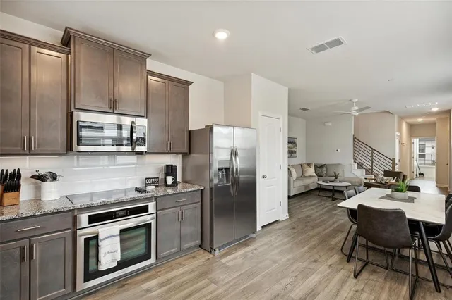 a kitchen with stainless steel appliances a stove a sink a refrigerator white cabinets and wooden floor