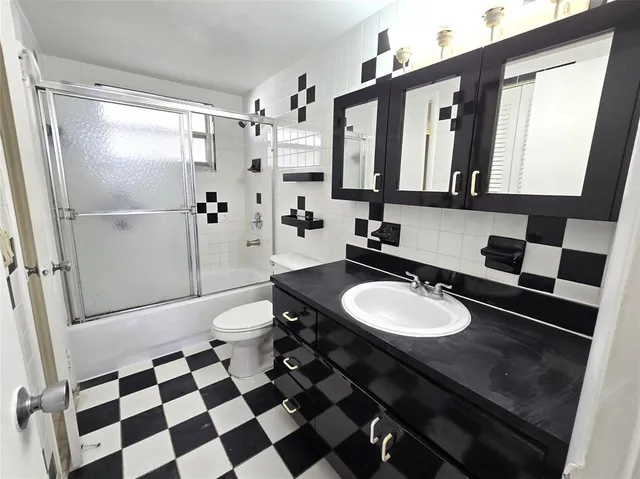 a bathroom with a sink a toilet a mirror and shower