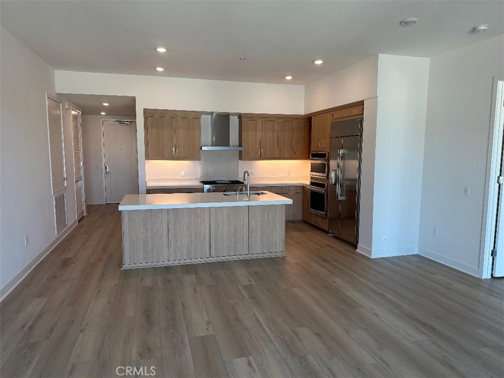 a large kitchen with stainless steel appliances granite countertop a large counter top and wooden floors