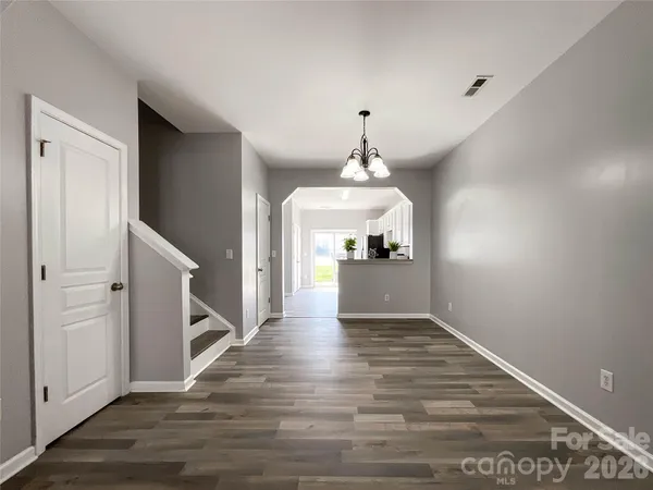 a view of a hallway with wooden floor and a kitchen