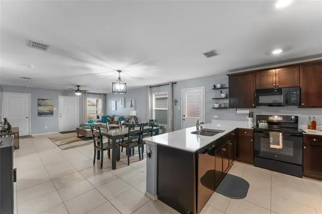 a dining hall with stainless steel appliances kitchen island granite countertop a sink table and chairs