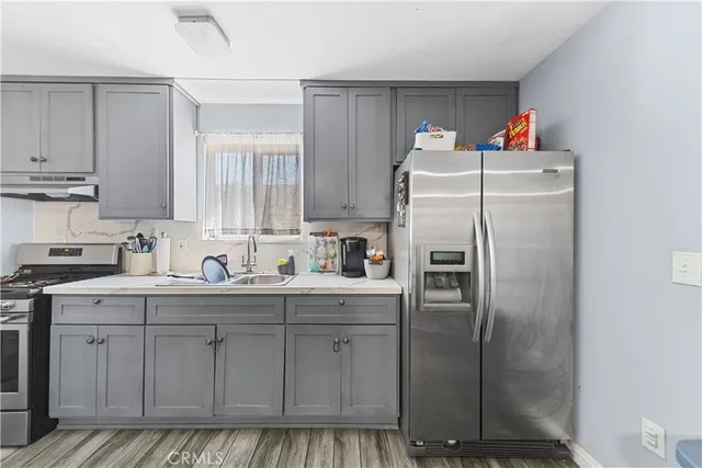 a white refrigerator freezer sitting inside of a kitchen with stainless steel appliances granite countertop a refrigerator a sink dishwasher and white cabinets with wooden floor