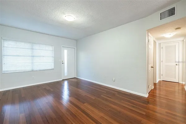 an empty room with wooden floor and windows