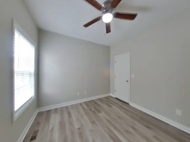 an empty room with a window and a fan