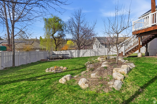 353 Robin Street Smithfield, UT 84335 - Photo 52 of 70 Fenced backyard with a trampoline, a fire pit, and a wooden deck