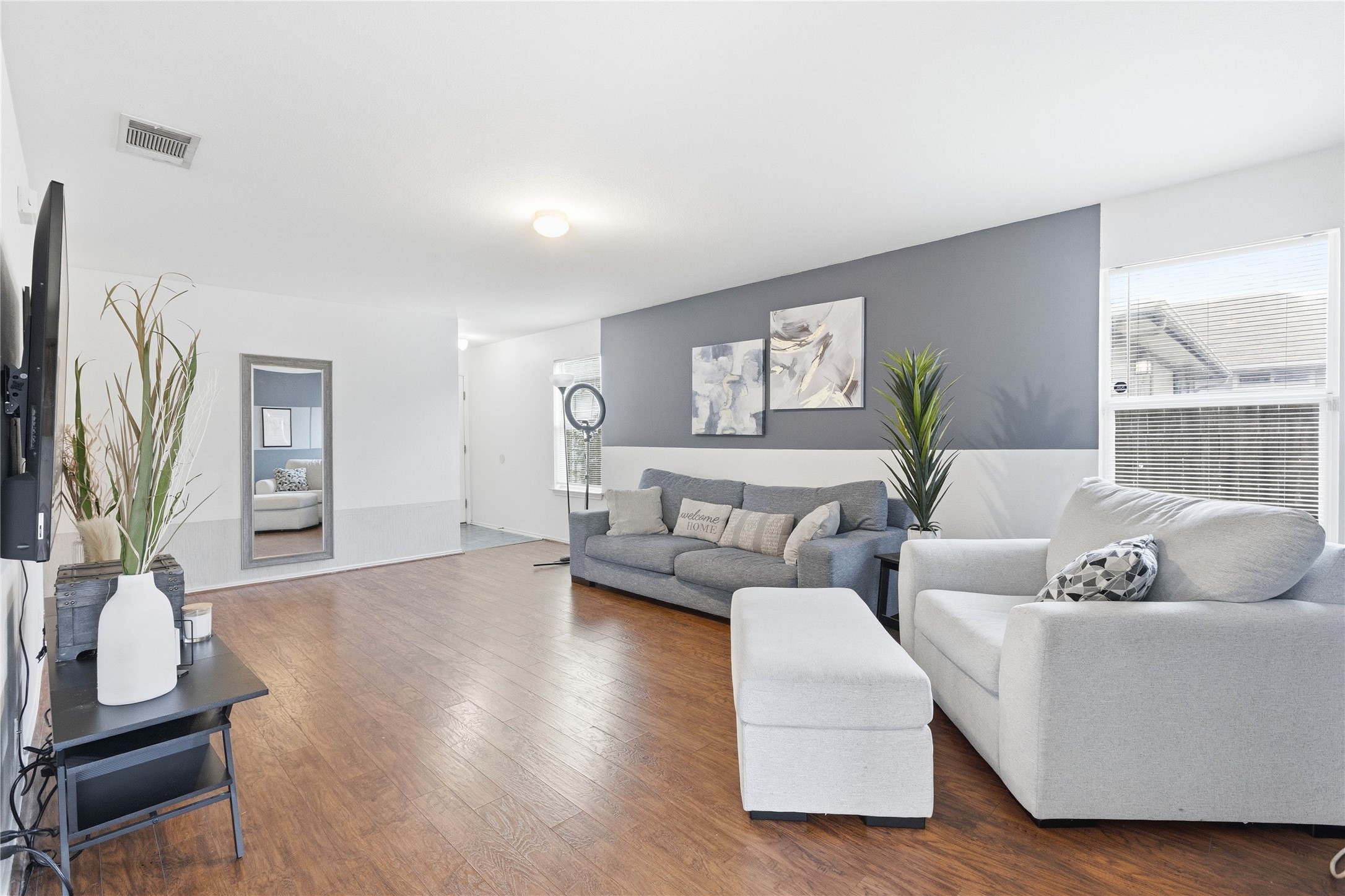 16112 Hamilton Point Circle Manor, TX 78653 - Photo 7 of 27 Spacious room featuring wood-finish flooring, a two-tone wall with a grey upper and white lower section, and a ceiling-mounted light fixture