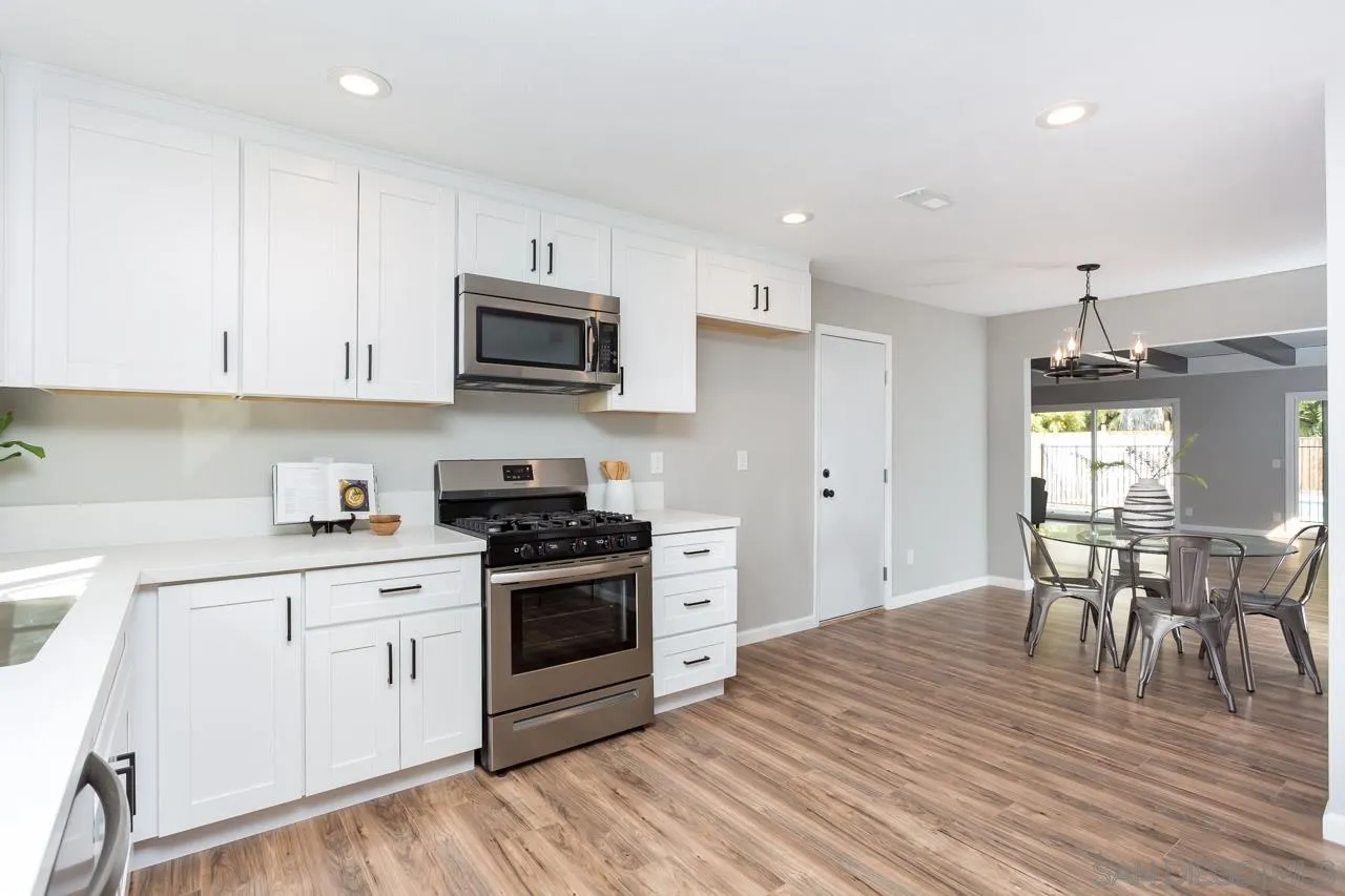 9597 Mandeville Road Santee, CA 92071 - Photo 9 of 32 a kitchen with stainless steel appliances granite countertop a stove top oven a sink dishwasher a dining table and chairs with wooden floor