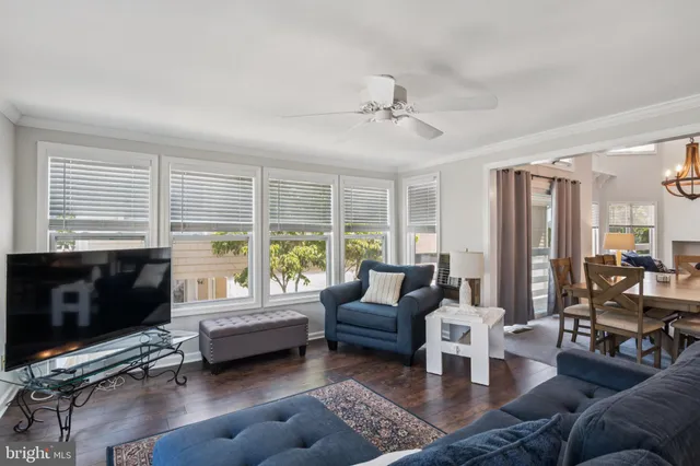 a living room with furniture floor to ceiling window hardwood floor and a flat screen tv