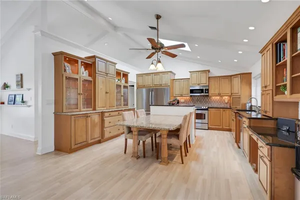 a kitchen with stainless steel appliances a dining table chairs stove refrigerator and cabinets