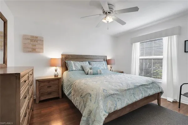 a bedroom with a bed a dresser with wooden floor