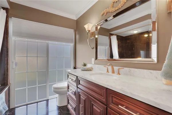 a bathroom with a granite countertop sink a toilet a mirror and shower