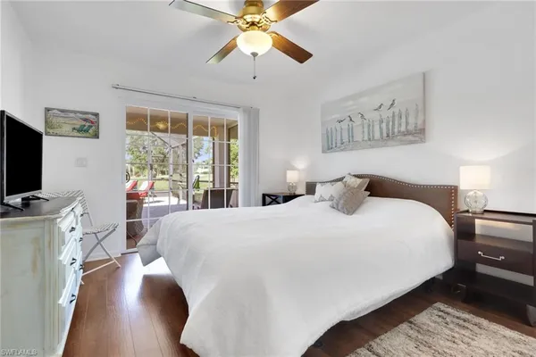 a bedroom with a large bed a flat tv screen and a chandelier