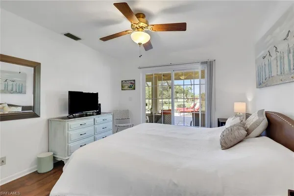 a bedroom with a large bed and a flat tv screen on dresser