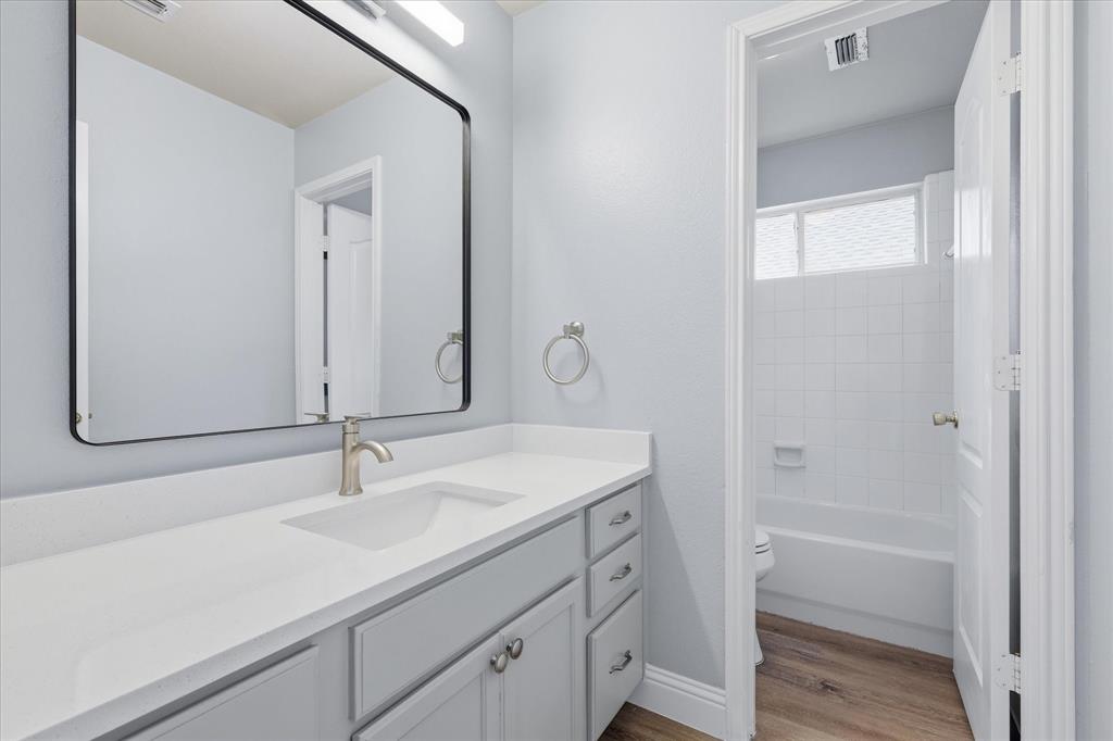 2616 Hollow Ridge Drive Denton, TX 76210 - Photo 27 of 31 Bathroom vanity featuring a rectangular mirror with a black frame, single basin sink, brushed nickel faucet, light-toned countertop, and light gray cabinetry with brushed nickel hardware