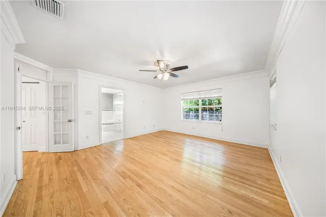 a view of empty room with wooden floor and fan